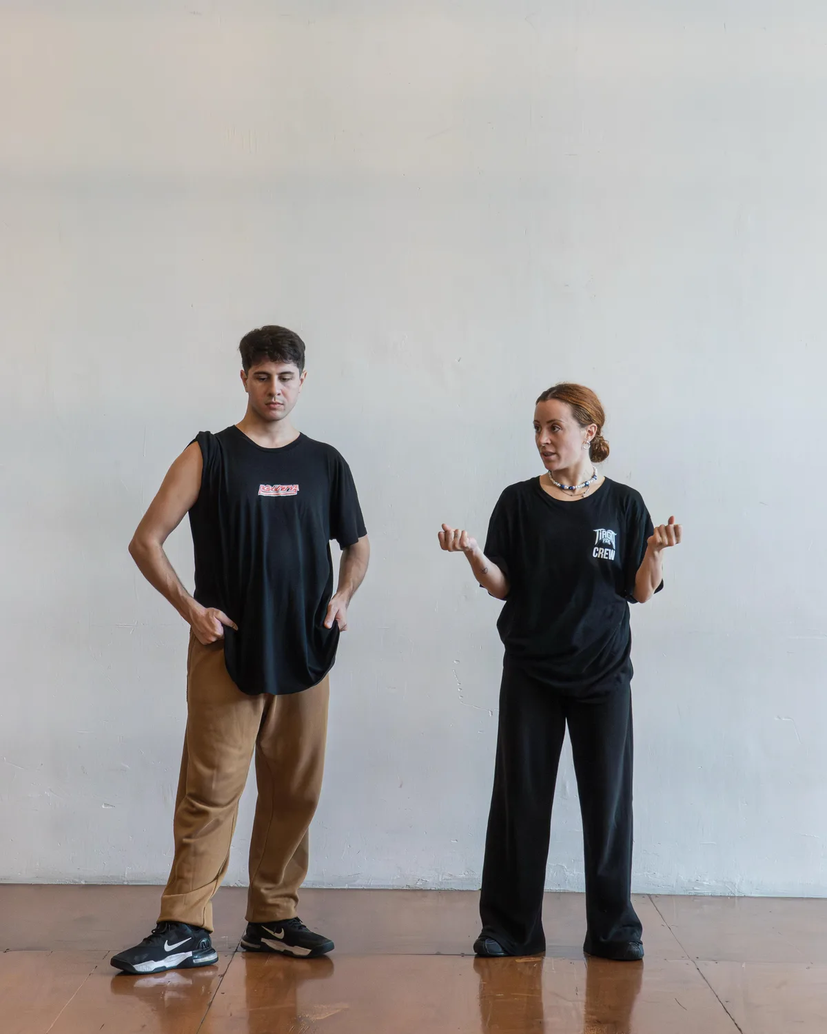 Dos instructores de pie frente a pared blanca