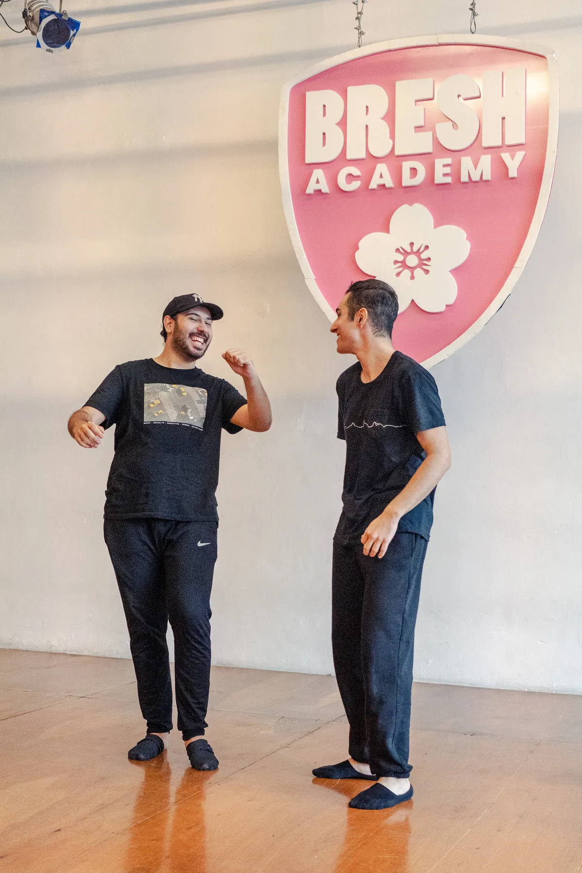 Docente y alumno frente al escudo de Bresh Academy